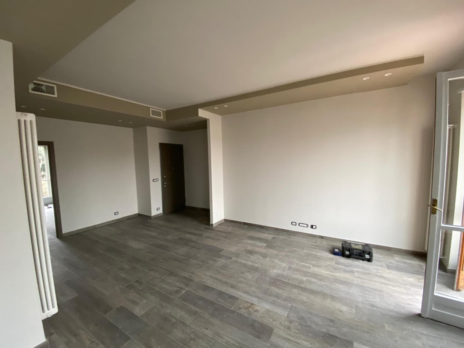 Zona living ristrutturata con pavimento effetto pietra e controsoffitto