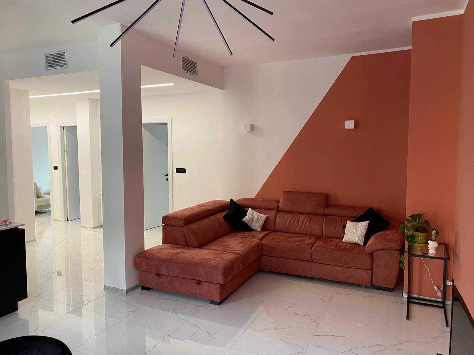 Zona living moderna con parete decorativa e pavimento effetto marmo